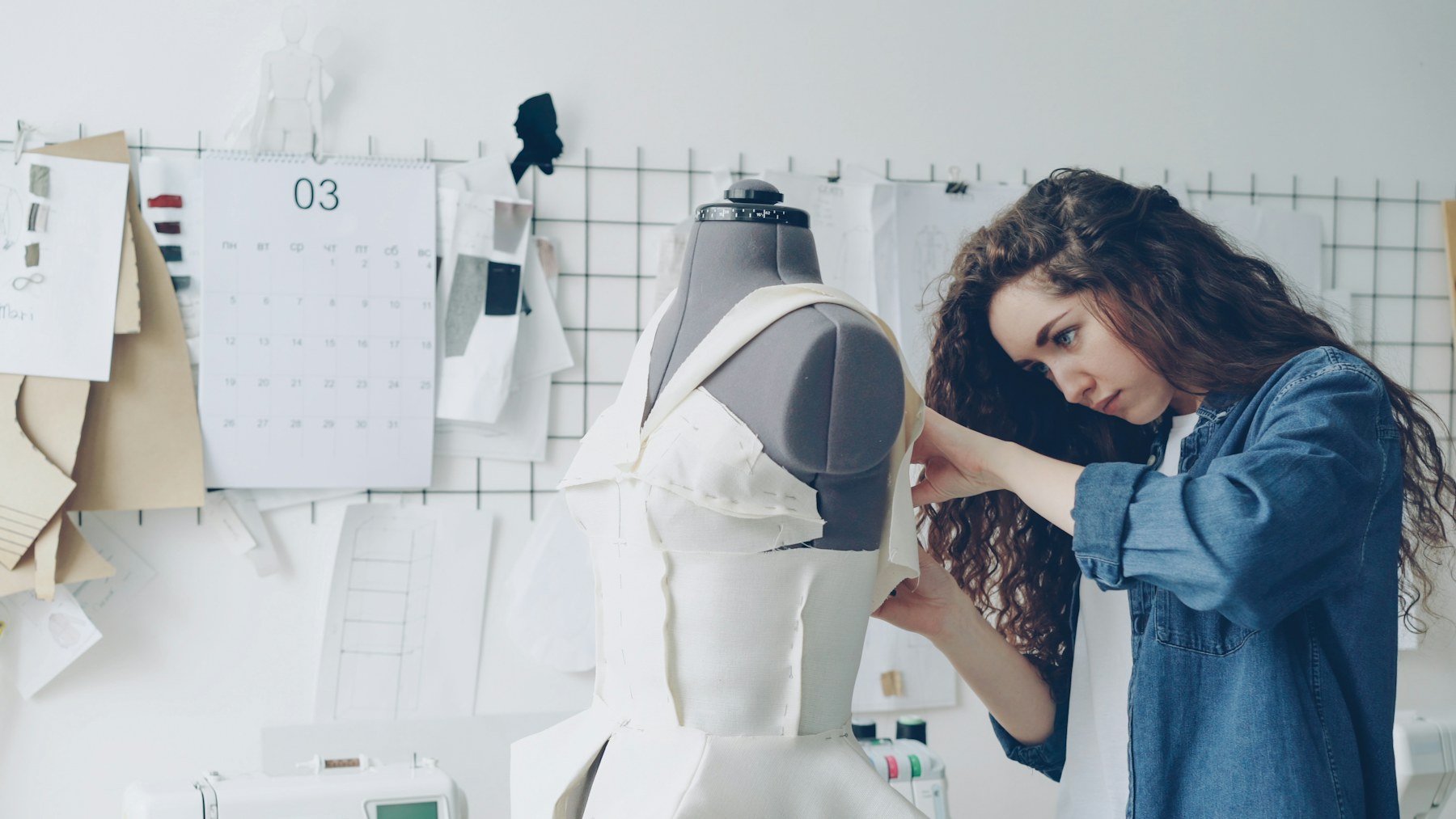 Fashion designer reviewing a garment on a dress form in a working studio